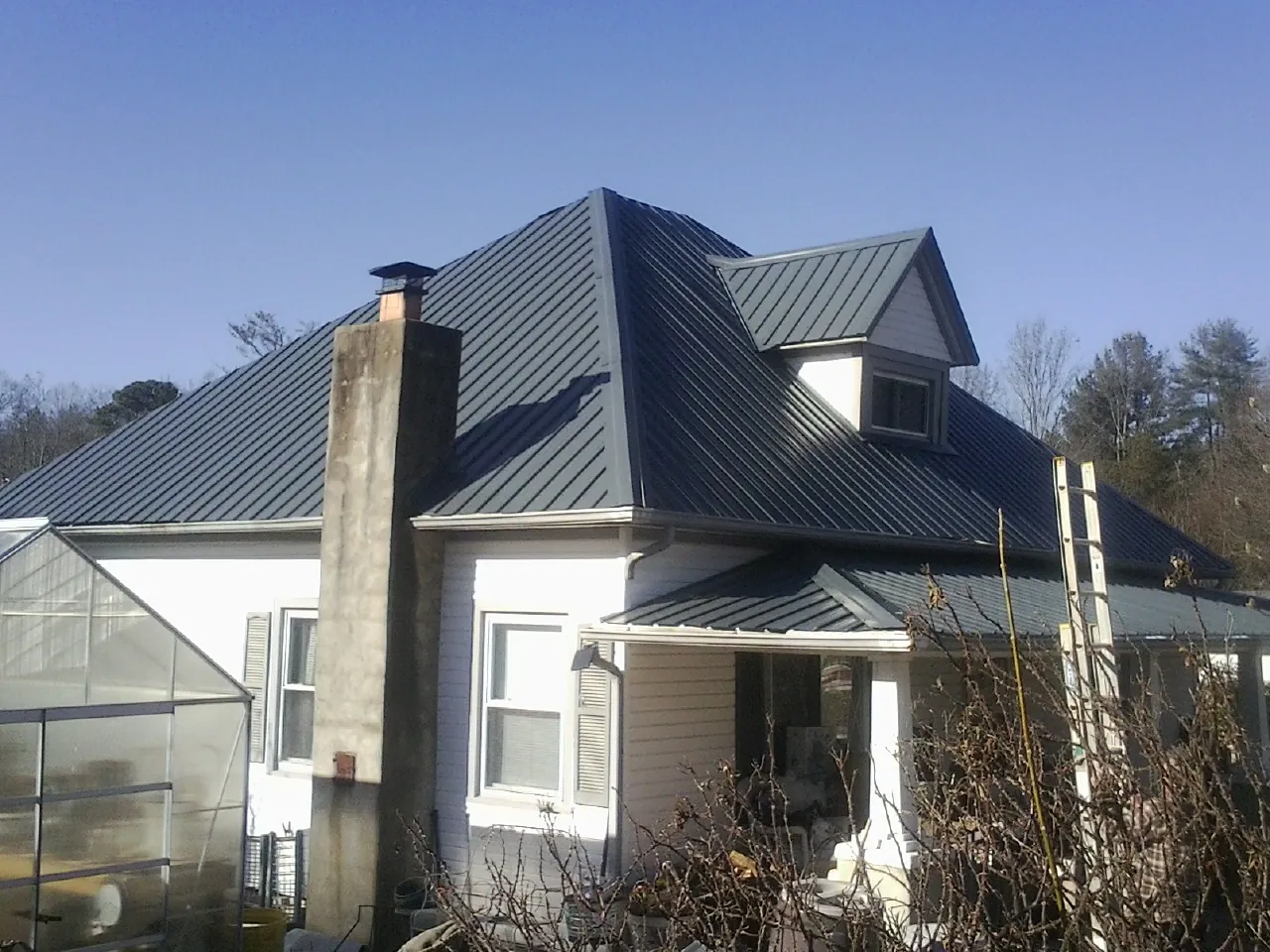 Dark blue standing seam metal roof on a white farmhouse with dormer — Slate & Tile Roof Repair by Roofing Brothers in Marriottsville