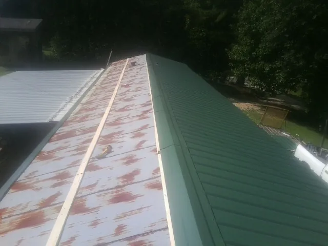 Old rusted panels beside newly installed green metal roofing — Wind Damage Roof Repair by Roofing Brothers in Marriottsville