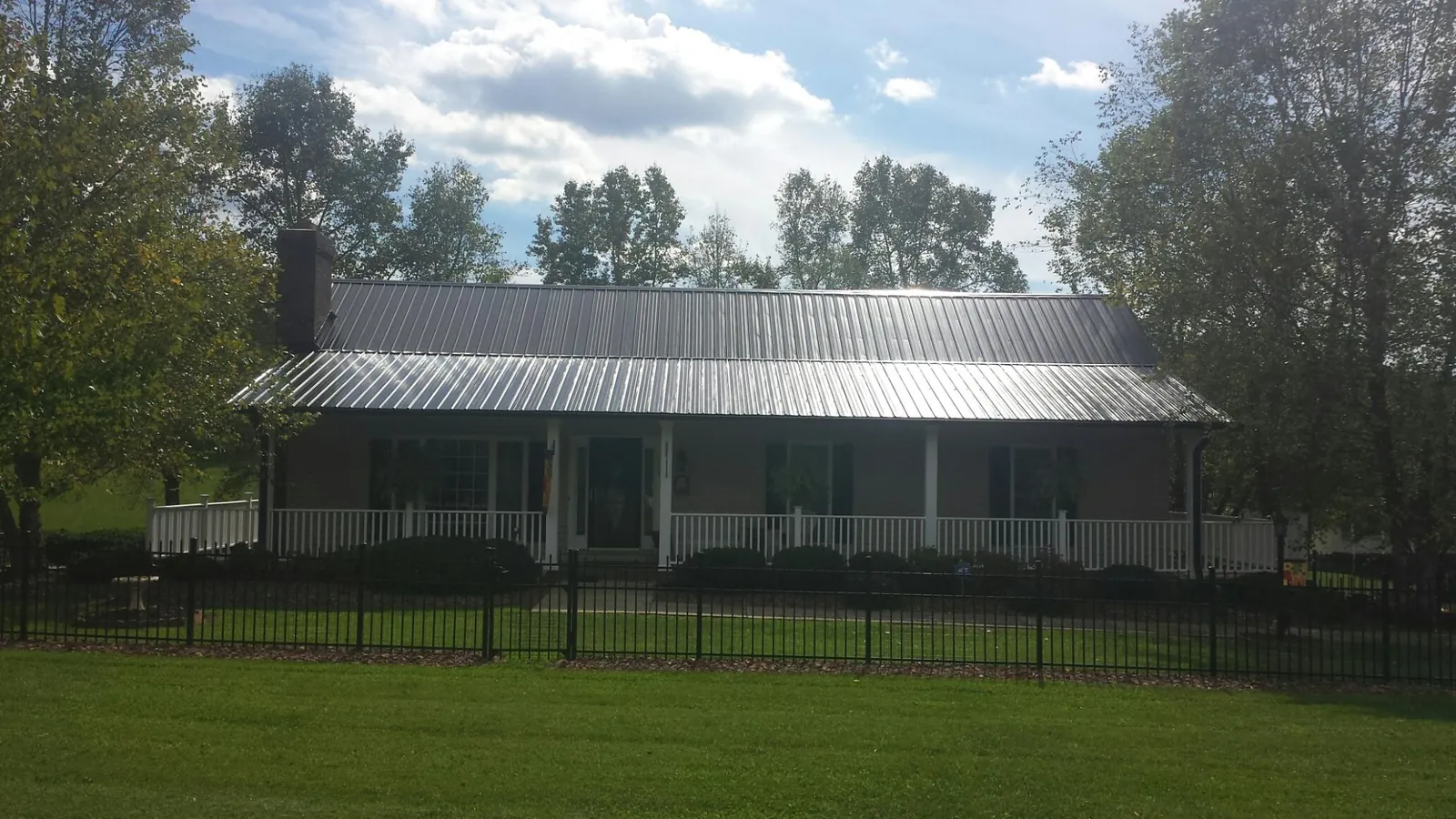 Gray metal roof on a brick ranch with a full width front porch — Gutter Guard Installation work by our crew in Marriottsville