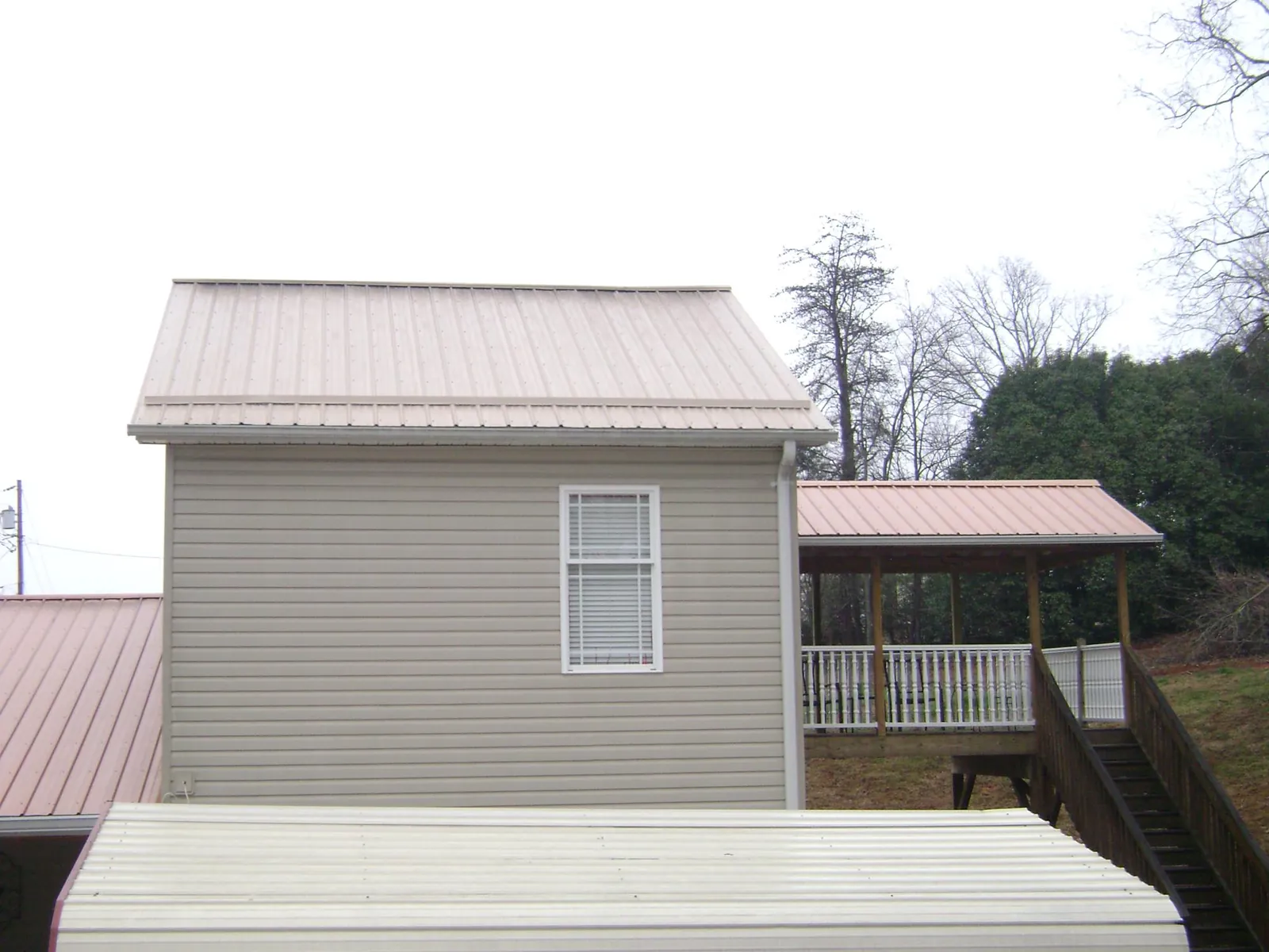 Tan metal roofs on a two story addition and attached porch, from a Roof Replacement job in Marriottsville