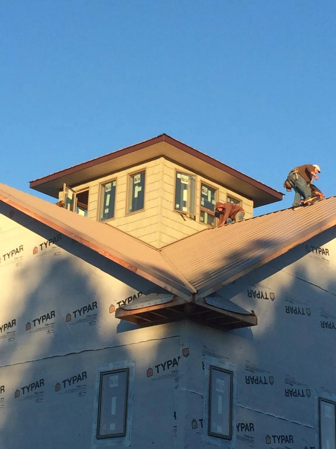 Roofers working around a rooftop cupola on a new metal roof at sunset — Roof Waterproofing in Marriottsville by Roofing Brothers